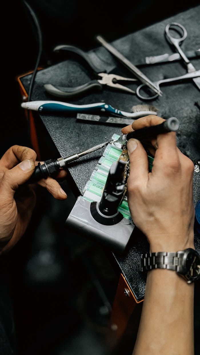 Hands soldering a circuit board with precision tools, showcasing detailed electronic craftsmanship.