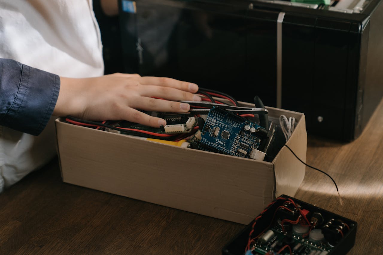 Close-up of hand interacting with Arduino microcontroller kit for electronic projects.